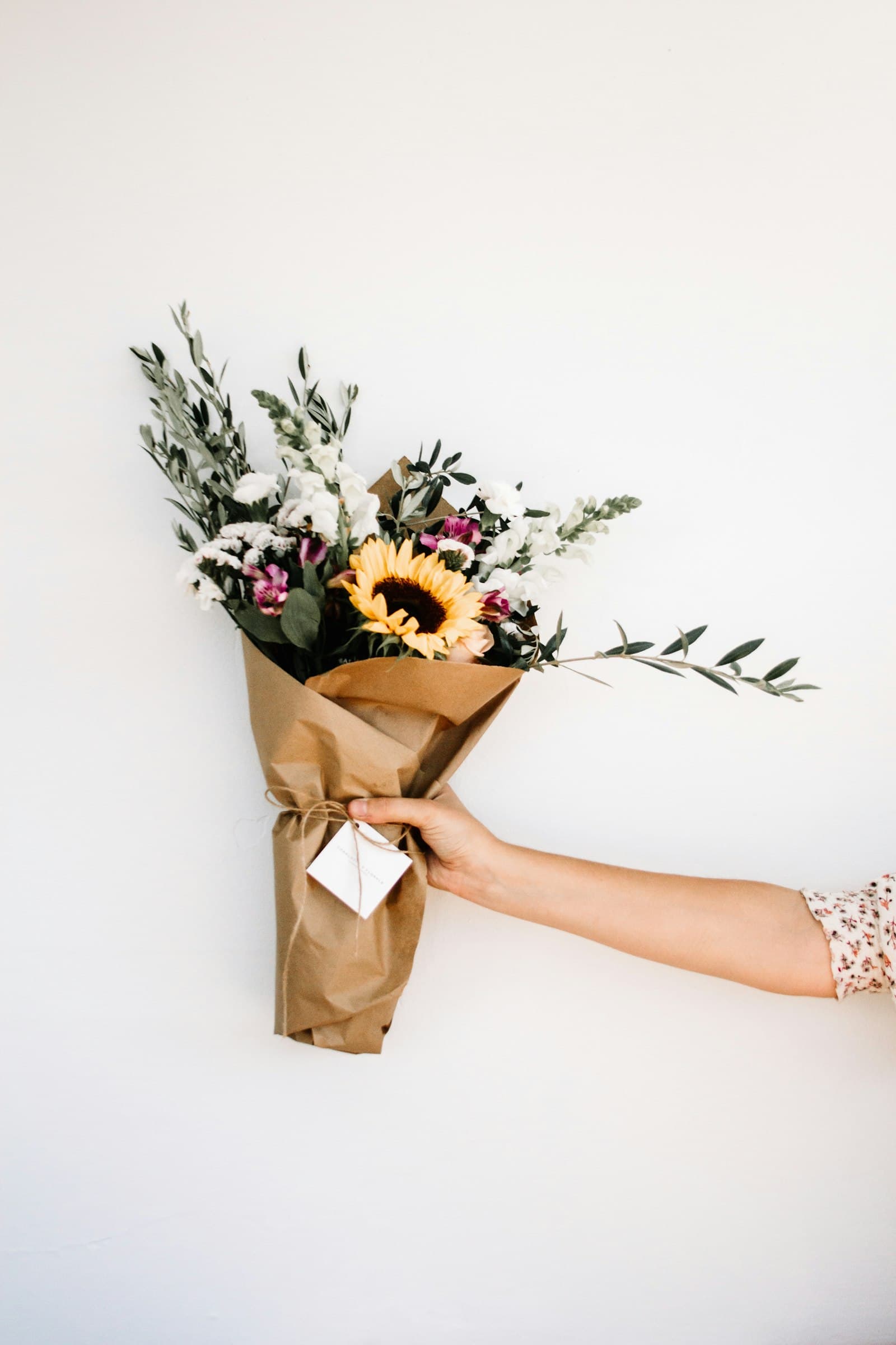 Kraft-wrapped wildflower bouquet with a sunflower held in hand